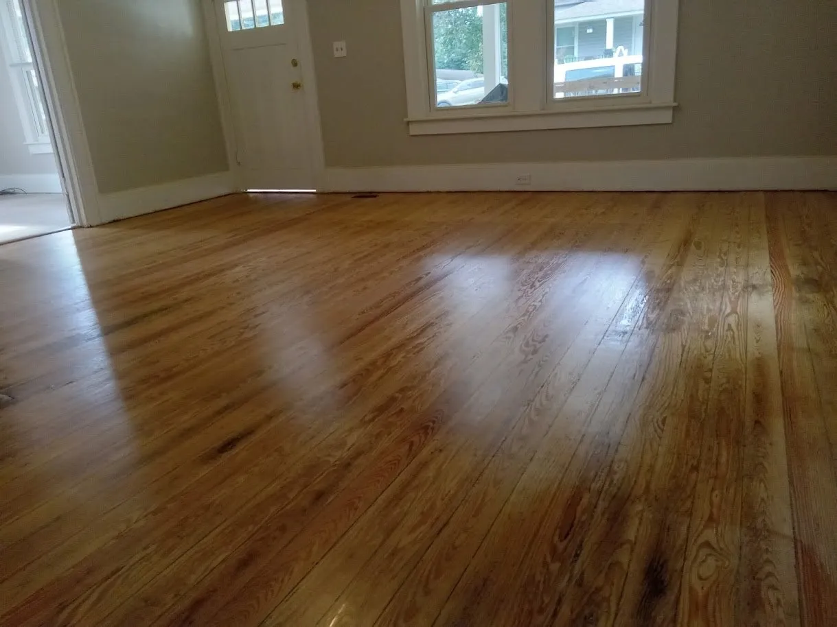 Refinished heart pine floor with a glossy amber finish in a sunlit front room