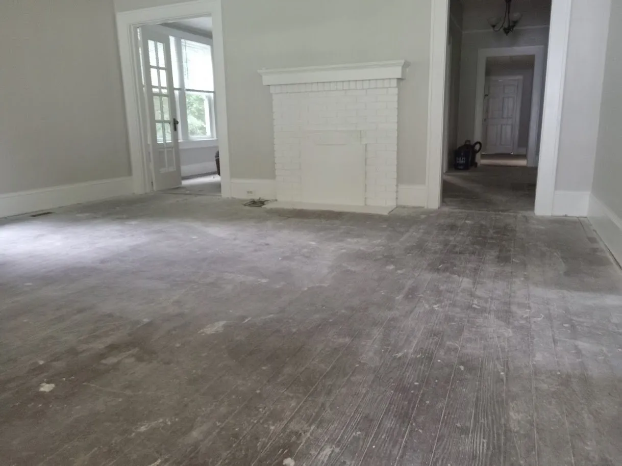 Same room mid-sanding, with grey paint residue still on the heart pine