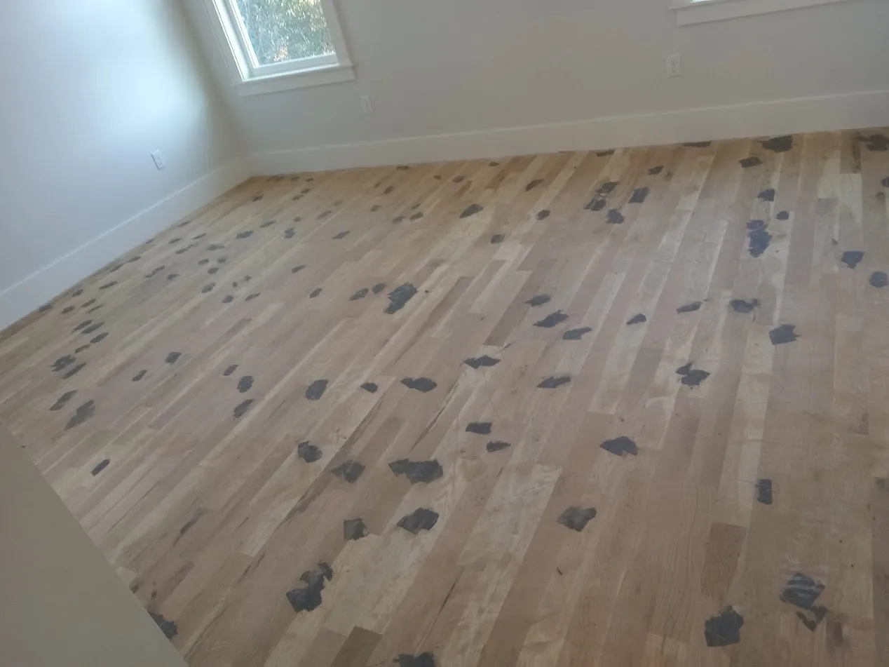 Newly installed white oak in a bedroom, trowel-filled before fine sanding