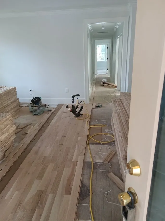 Raw white oak boards being installed over the old subfloor in a hallway