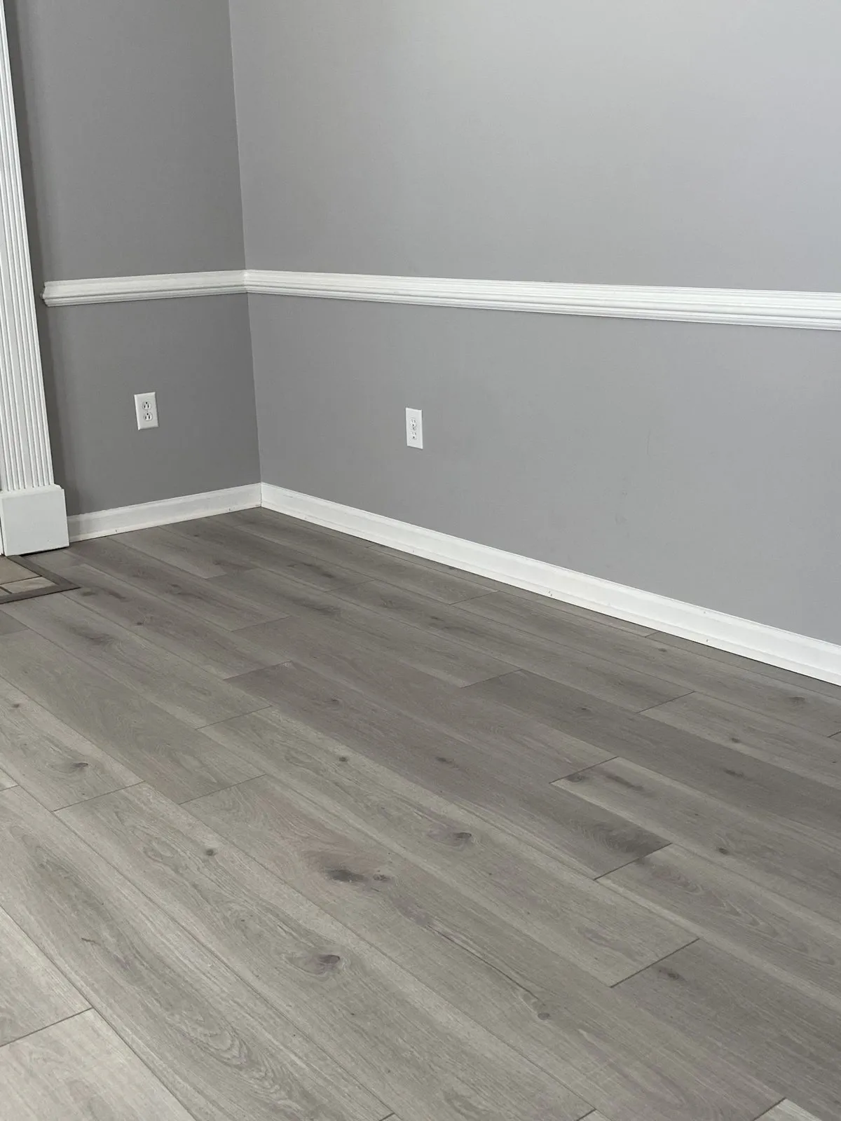 Grey wood-look plank flooring in a room with white chair rail