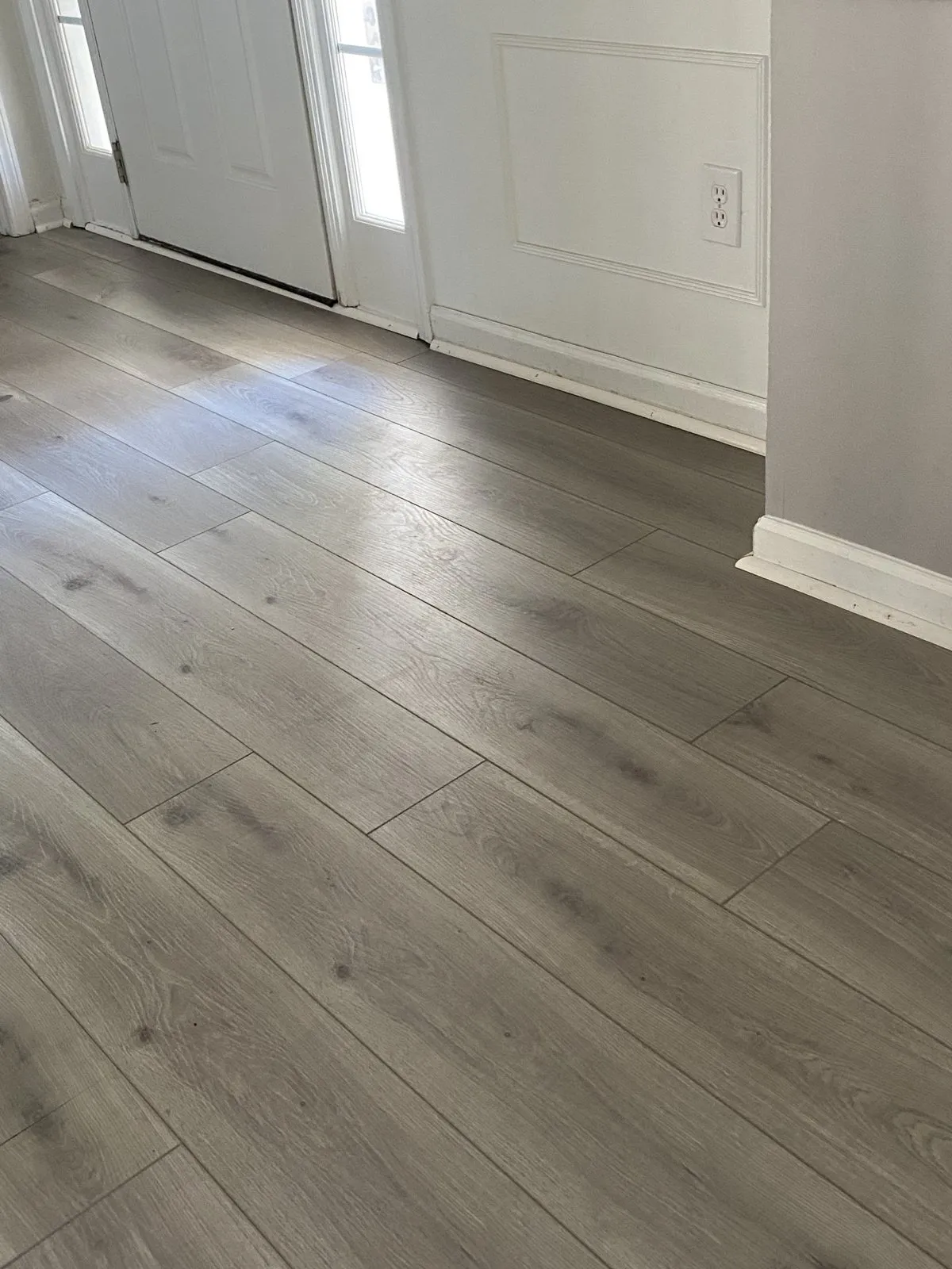 Grey plank flooring running to the front door